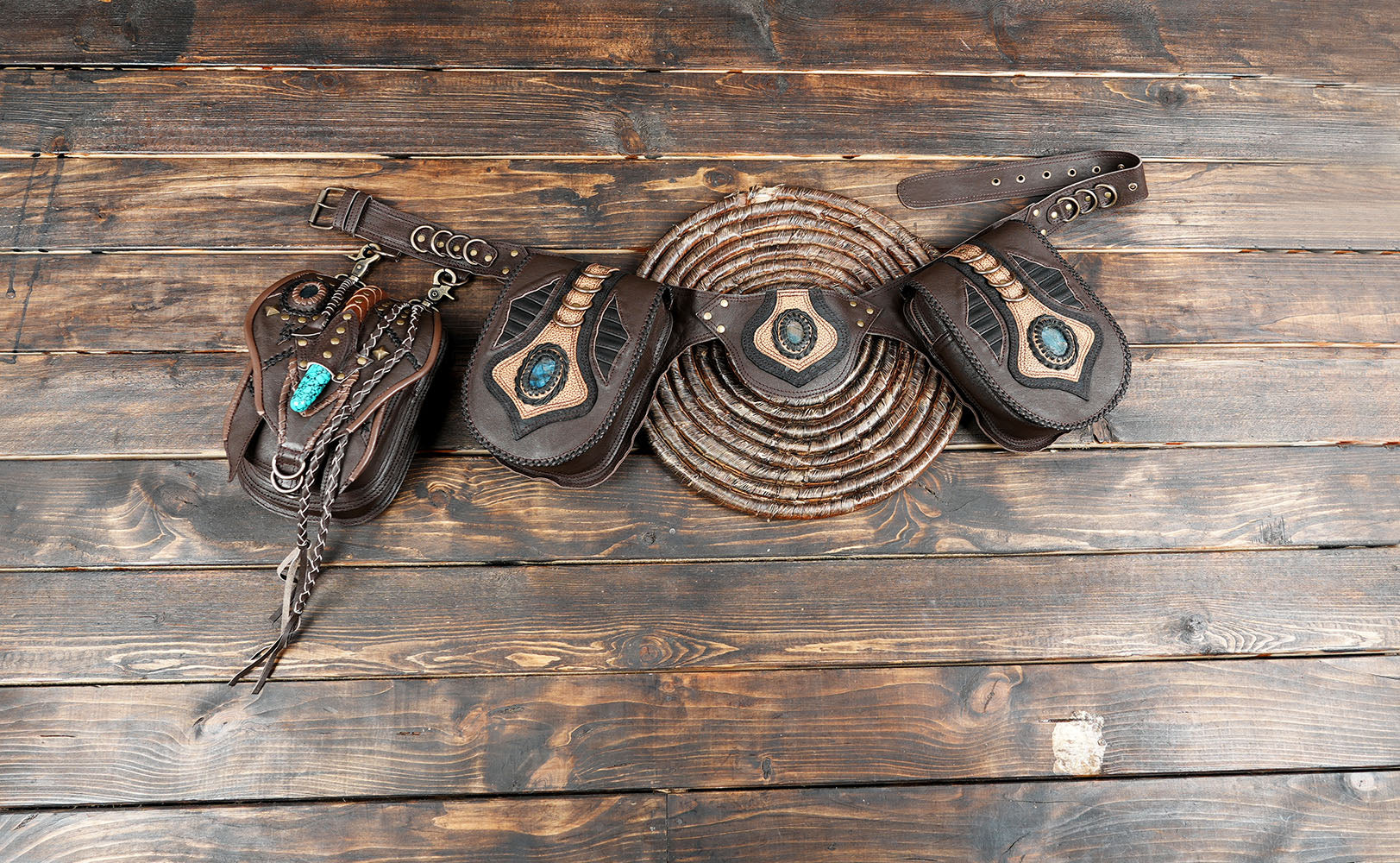 Handmade brown leather utility belt with blue gemstone centerpiece on rustic wood background