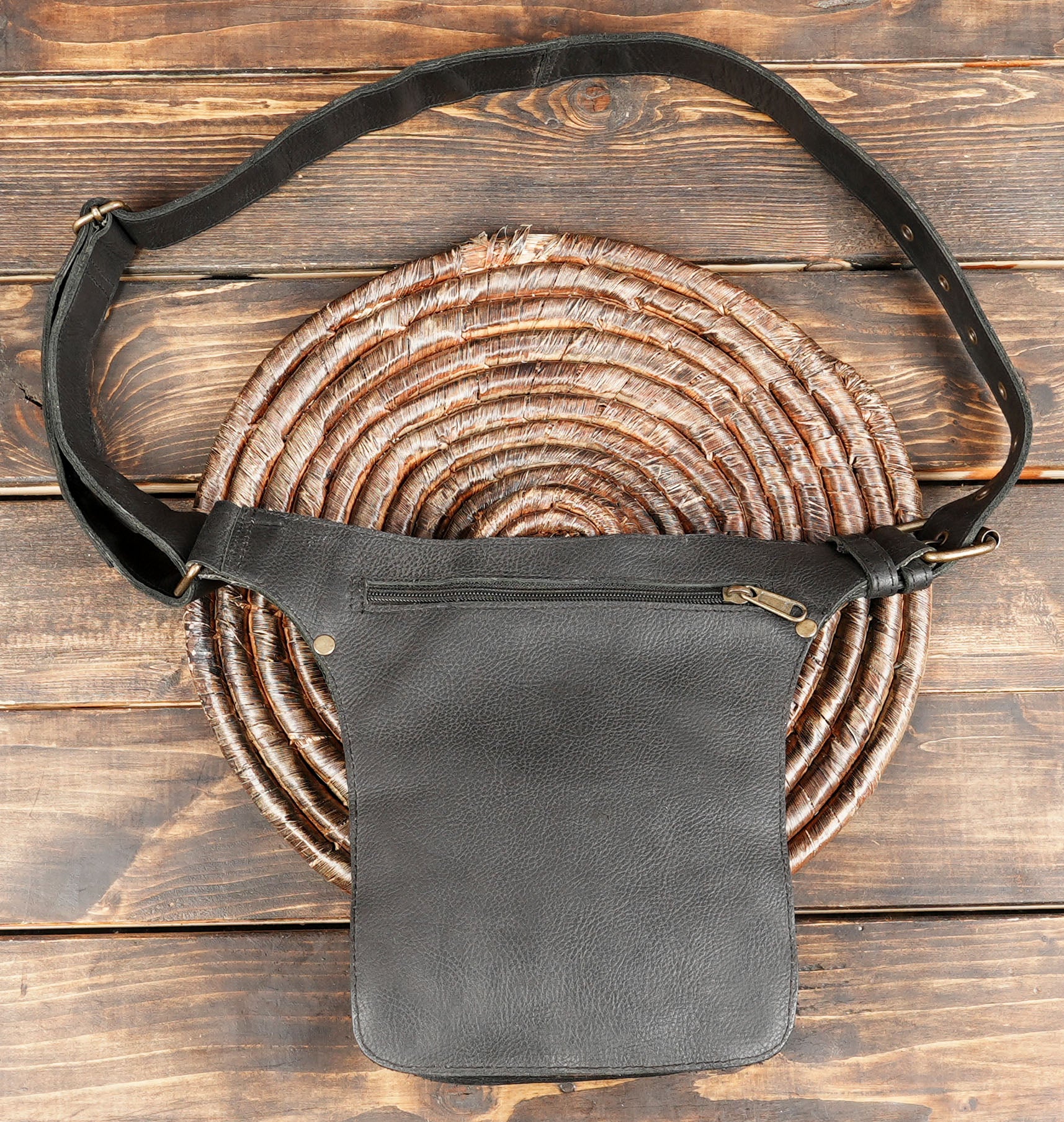 Black leather fanny pack with front clasp and zipper pocket design.