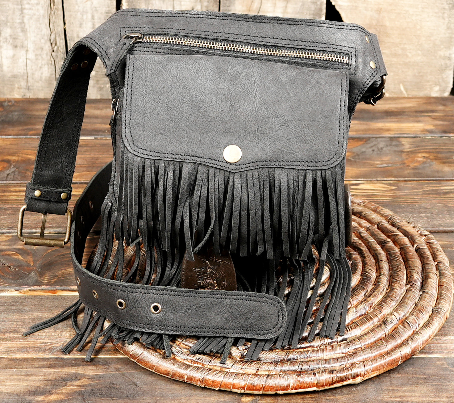 Black leather fringe fanny pack with zipper compartment and snap flap.