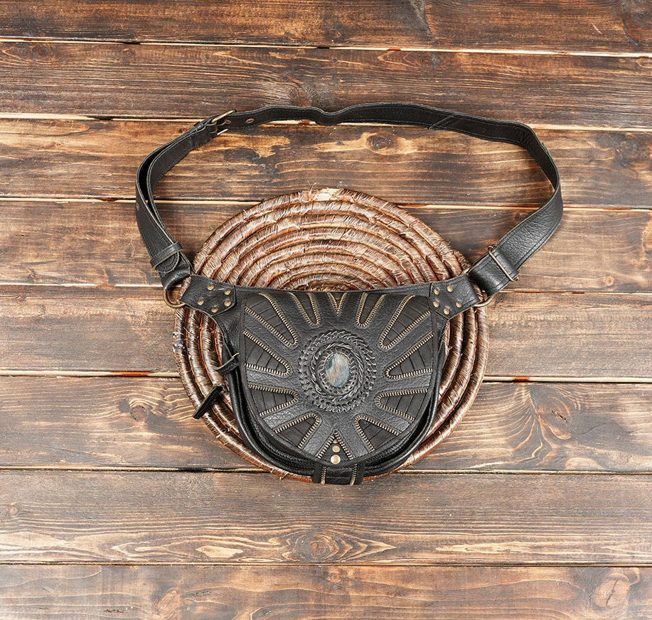 Handmade black leather belt bag with gemstone centerpiece on rustic wood background