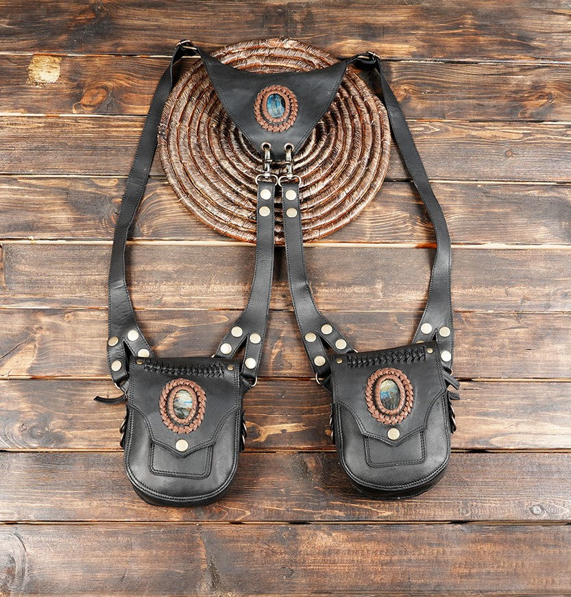 Black leather dual holster bag with gemstone centerpiece on wooden table