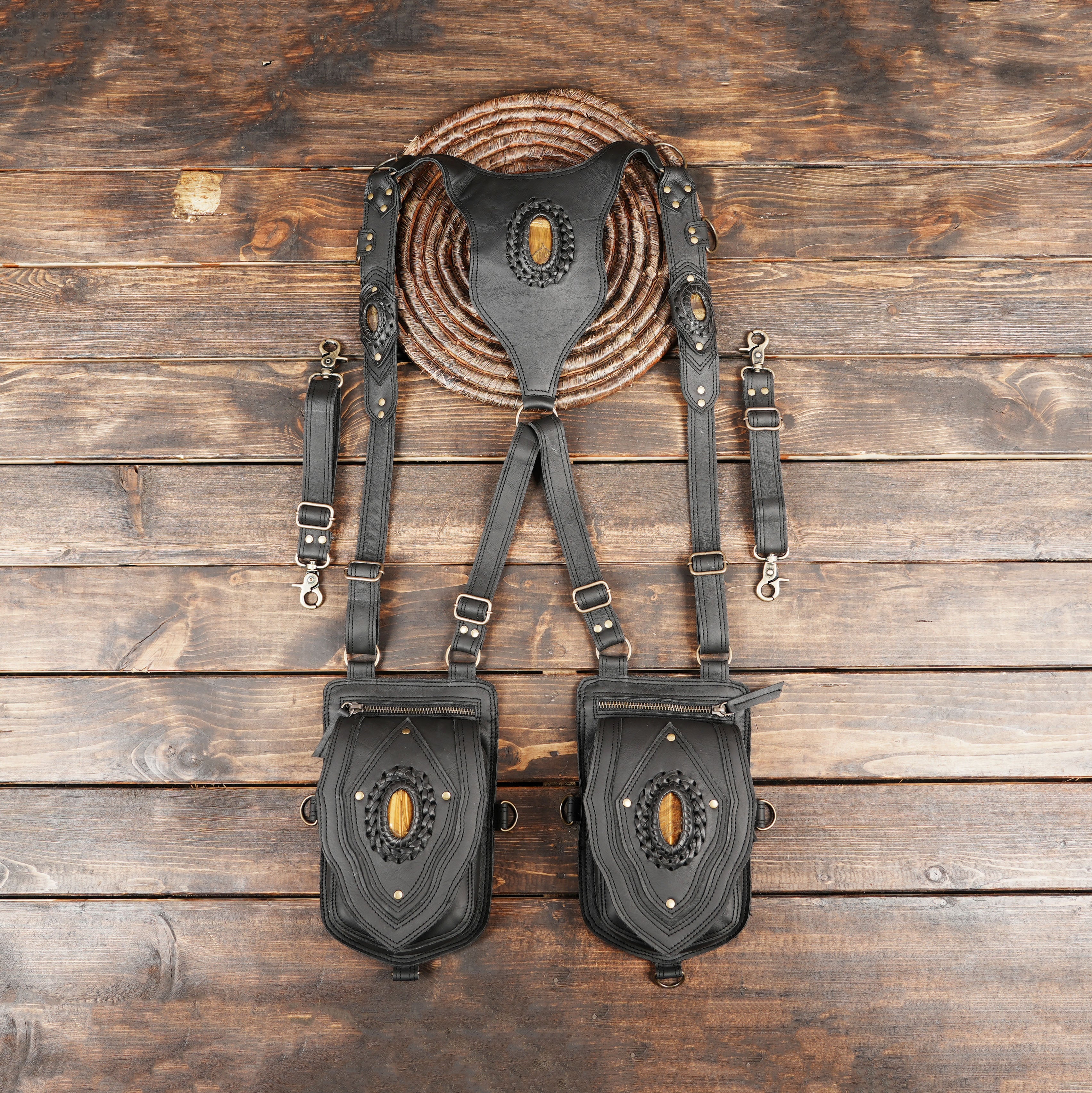 Black leather shoulder holster bag with gemstone centerpiece on wooden background