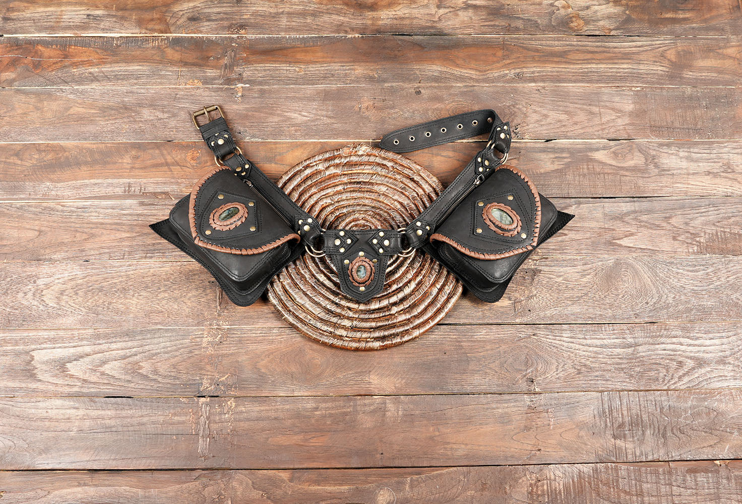 Handmade leather utility belt with gemstone centerpiece on wooden background
