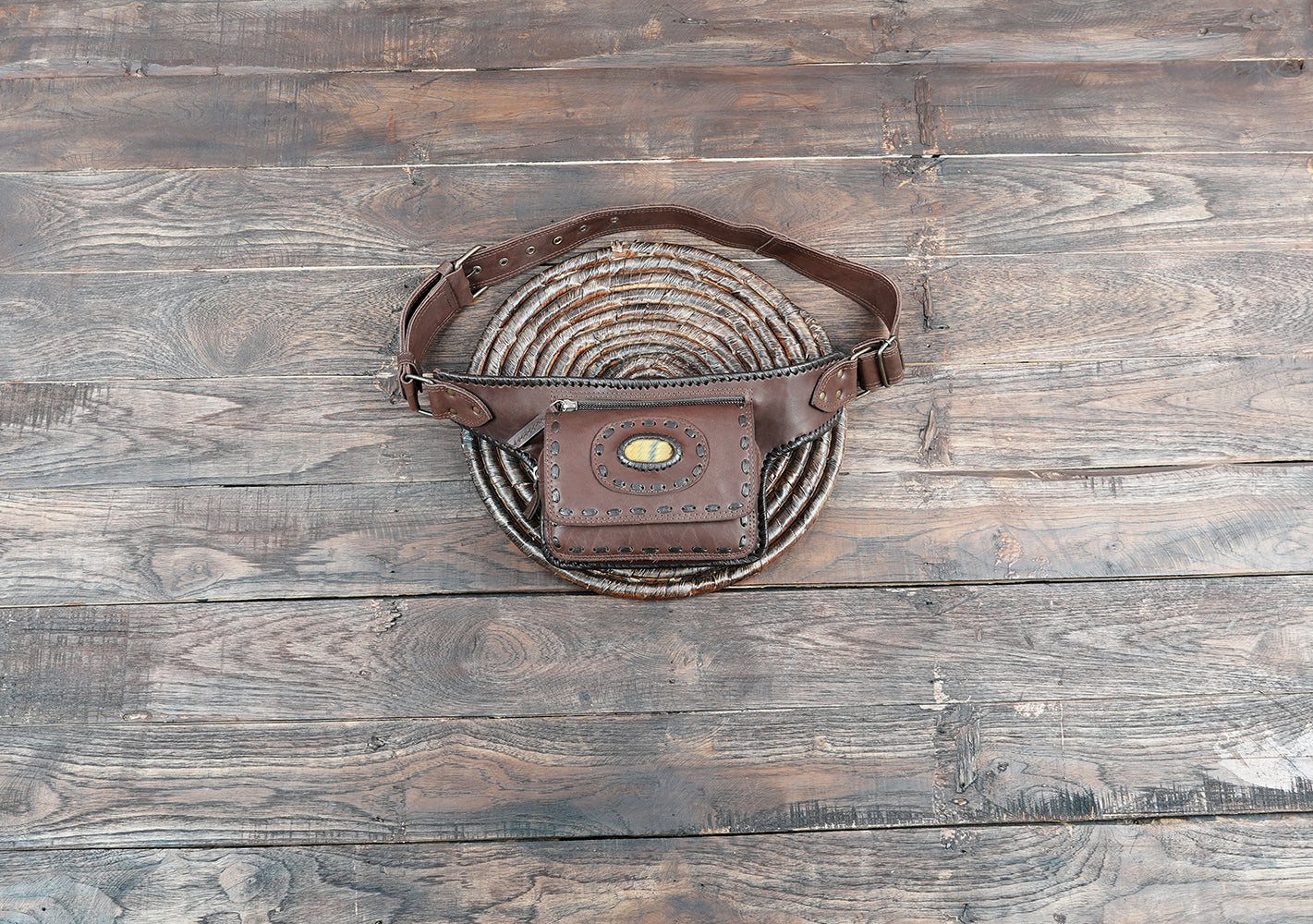 Handcrafted brown leather belt bag with natural stone accent and detailed stitching
