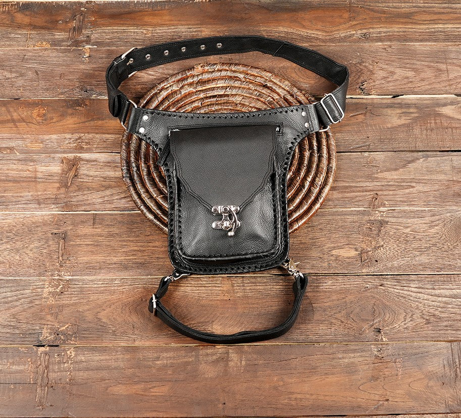 Handmade black leather thigh bag with silver clasp on wooden background