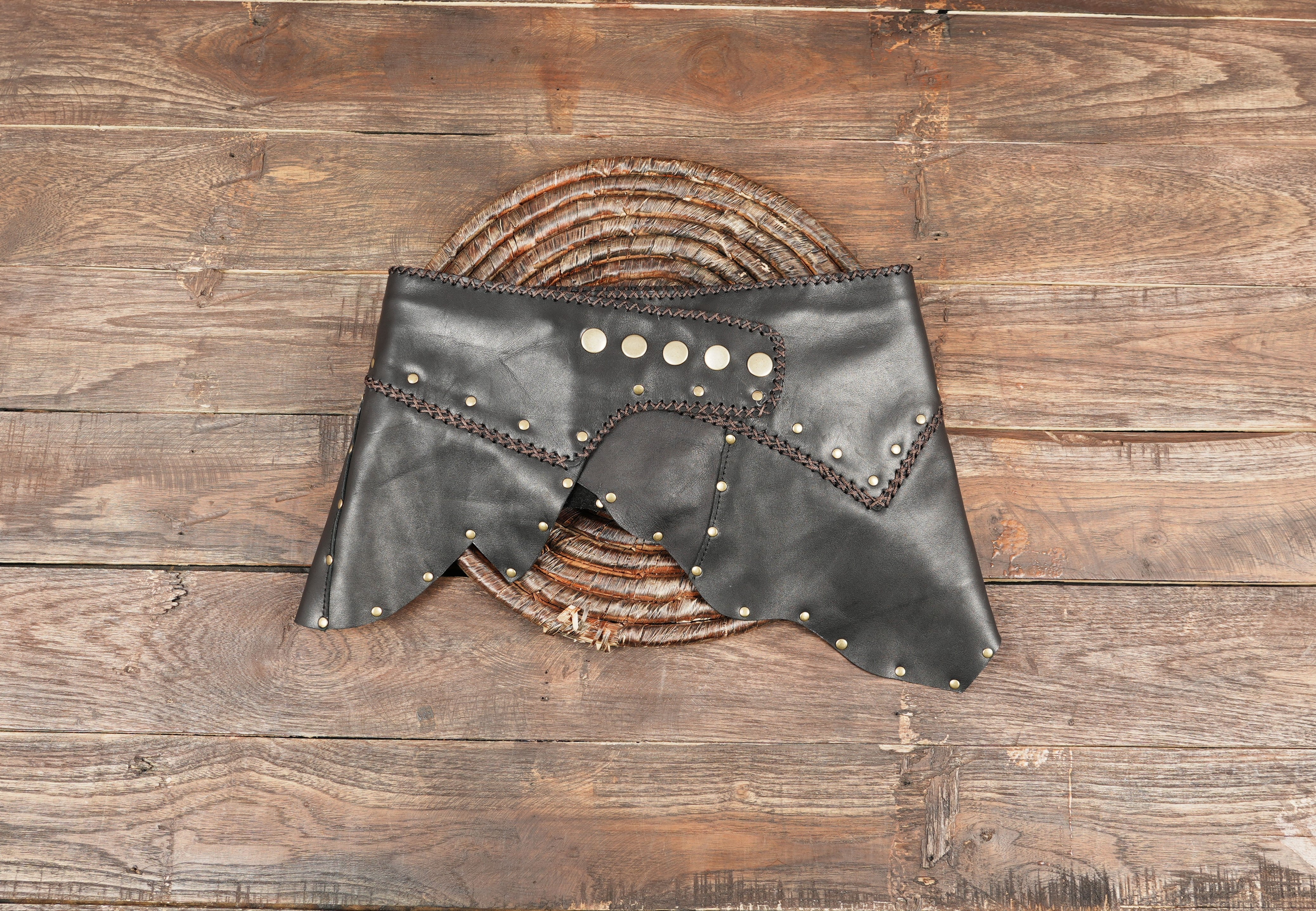 “Handmade black leather skirt with brass studs and cross-stitch trim, gothic steampunk festival wear.”