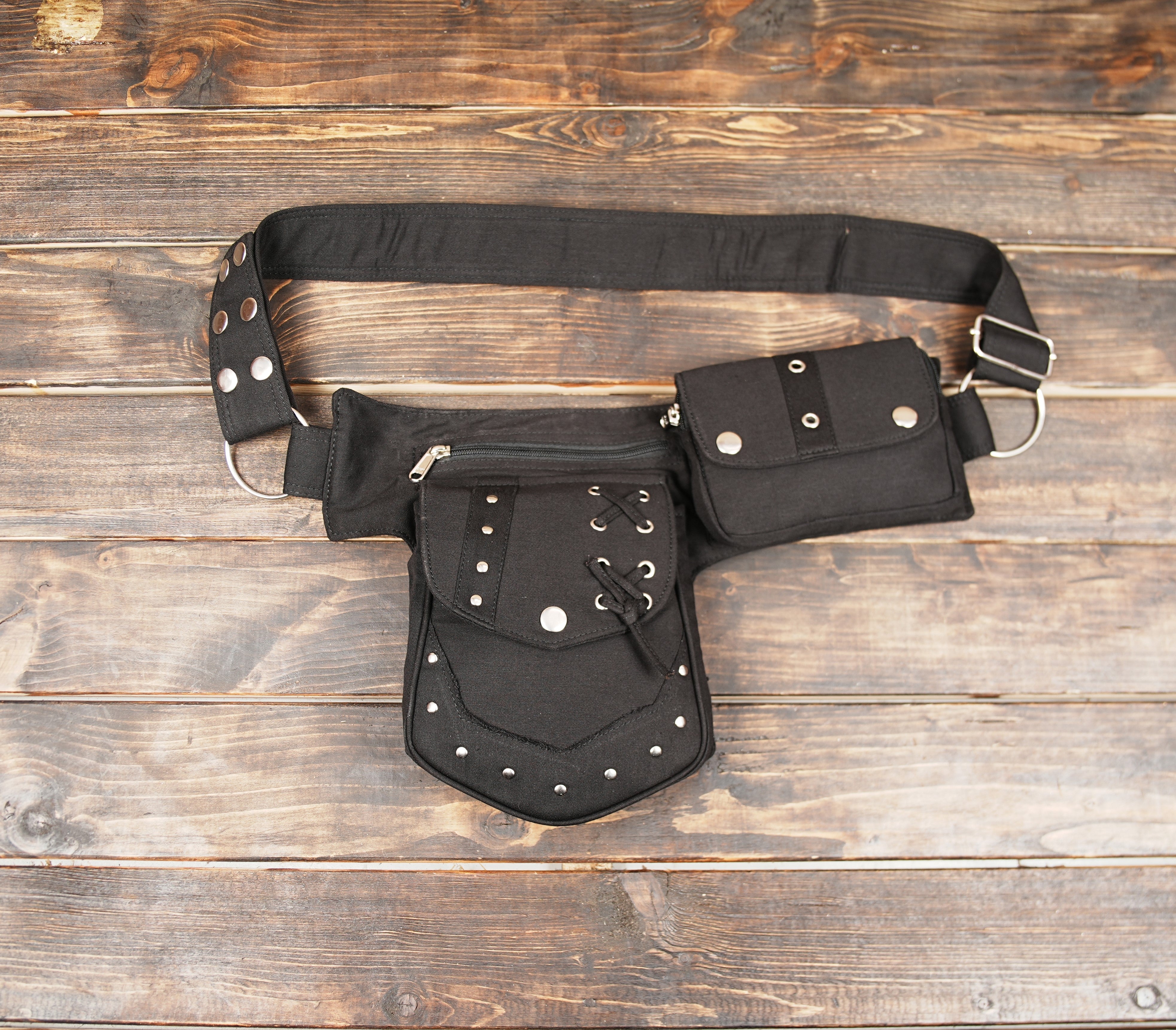 Black cotton waist bag with rivet details on wooden background