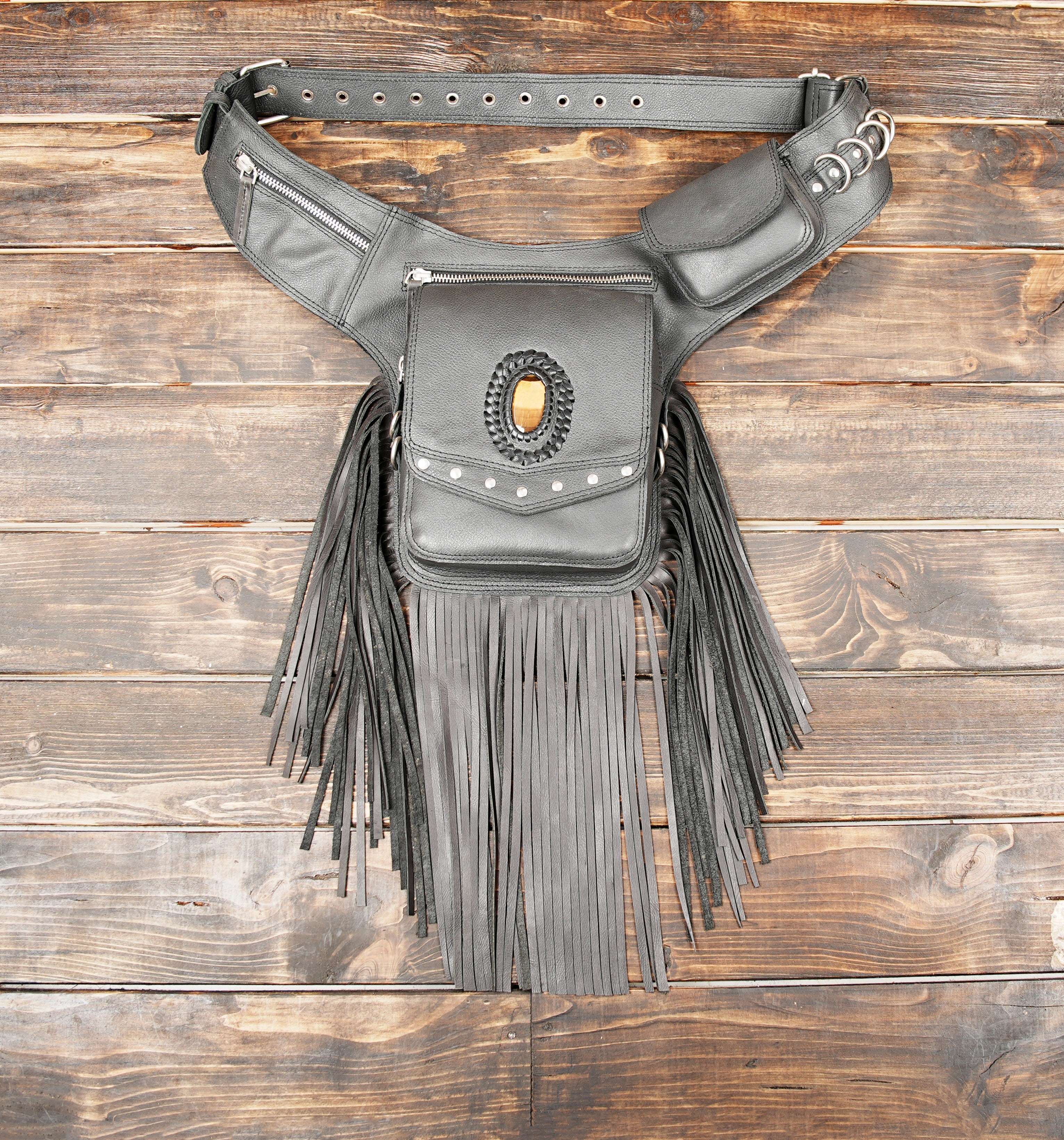 Black leather waist belt bag with long fringe and gemstone centerpiece.