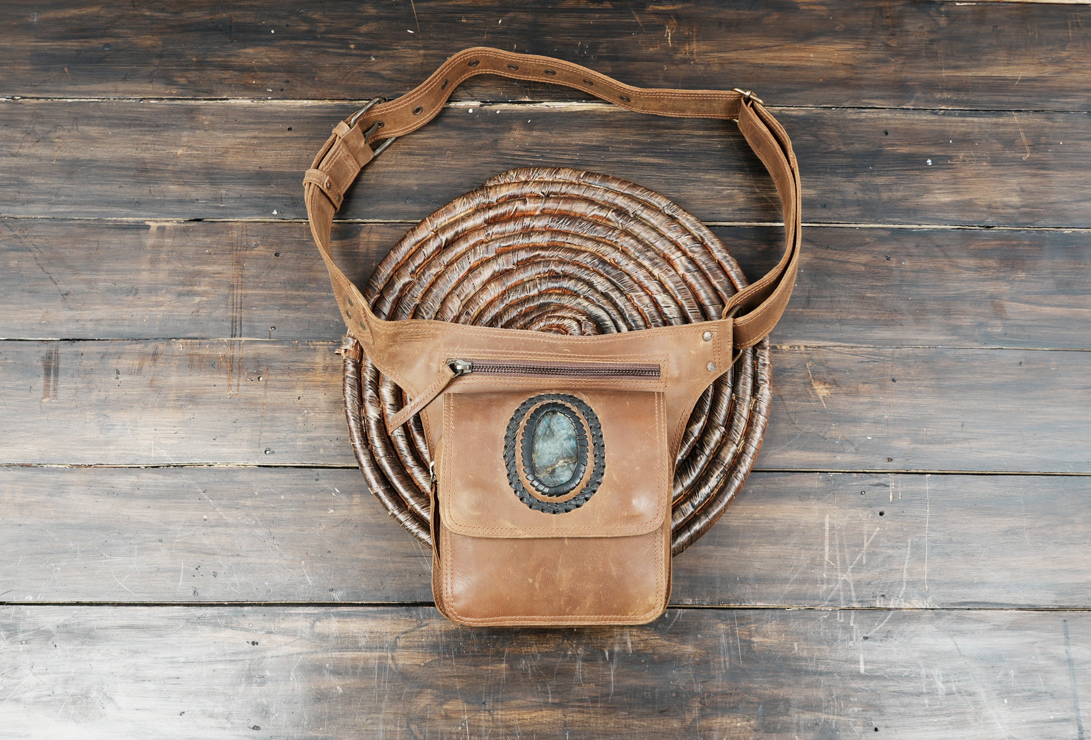 Brown leather waist bag with gemstone detail displayed on rustic wood background