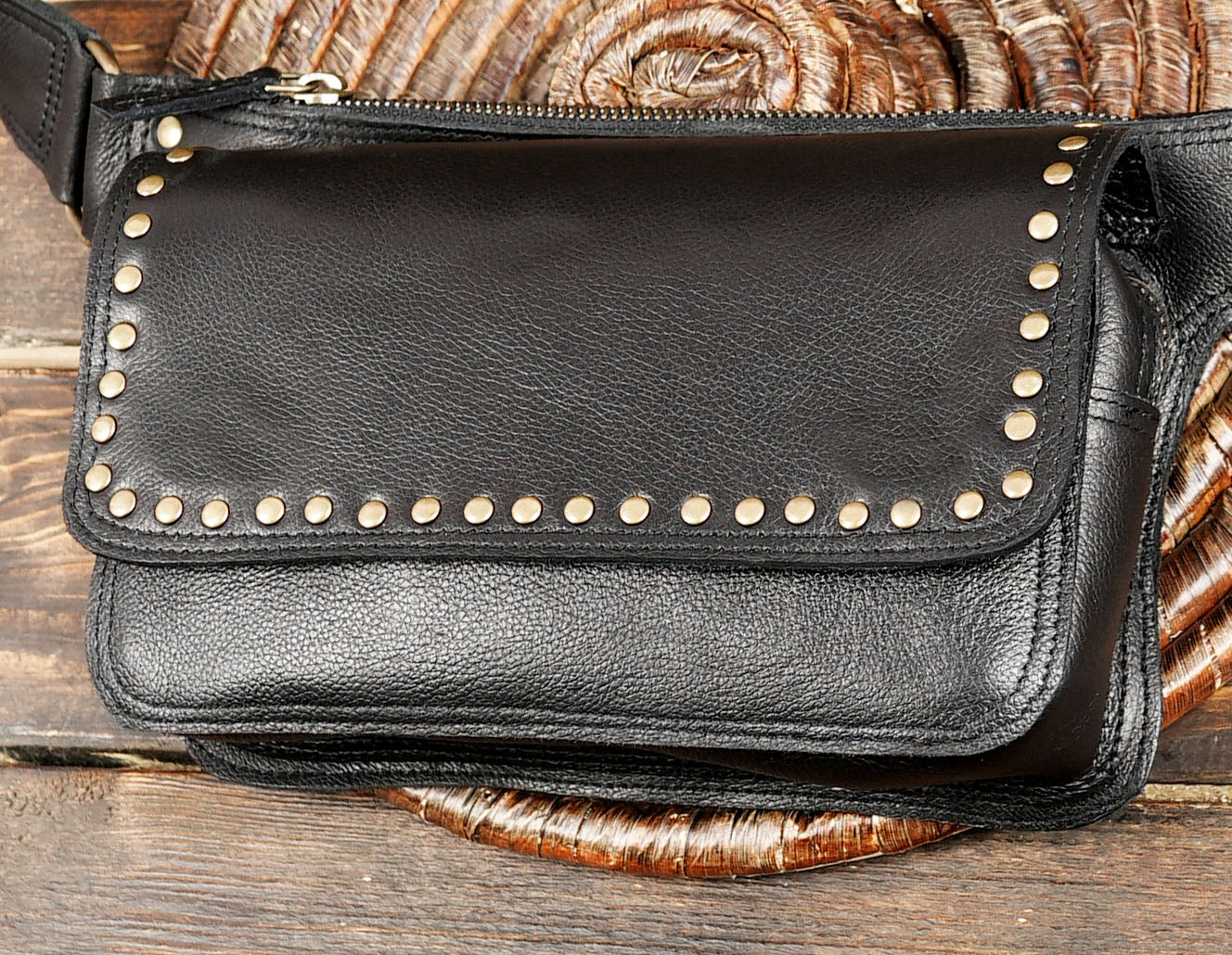 Close-up of black leather utility belt pouch with antique brass rivets