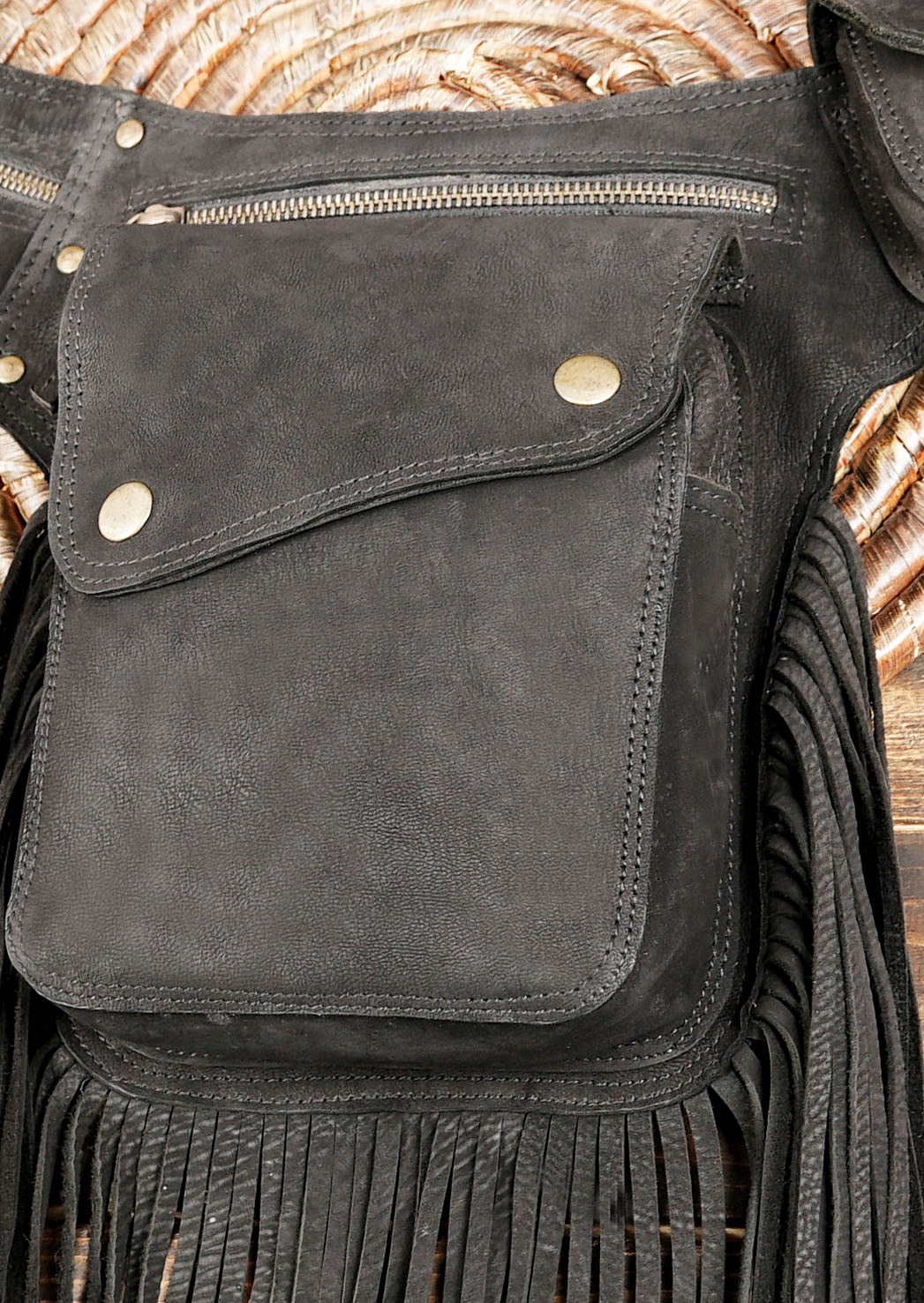 Backside view of cotton waist bag with fringe and zipper pocket