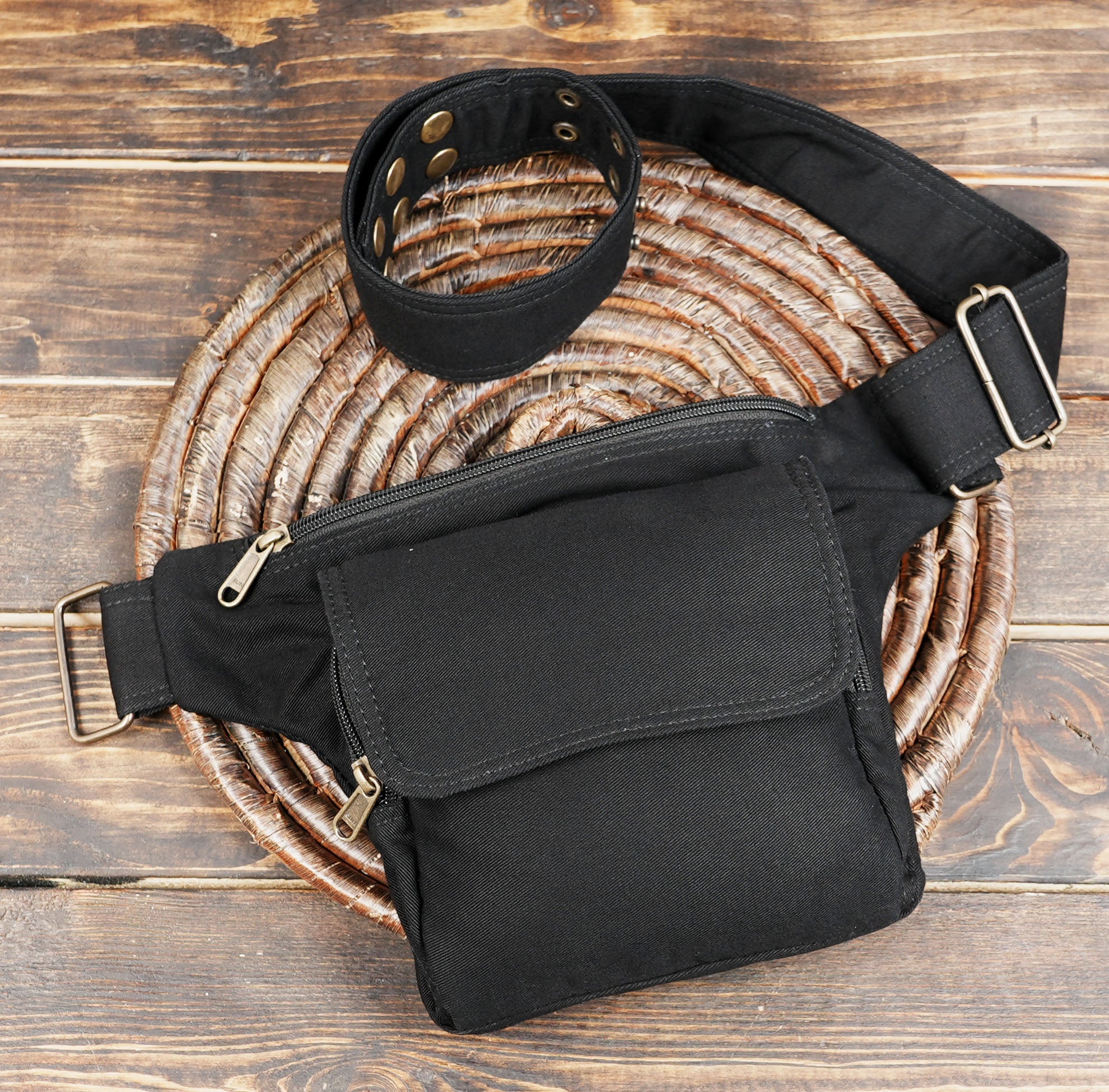 Side view of black canvas hip bag with zippers