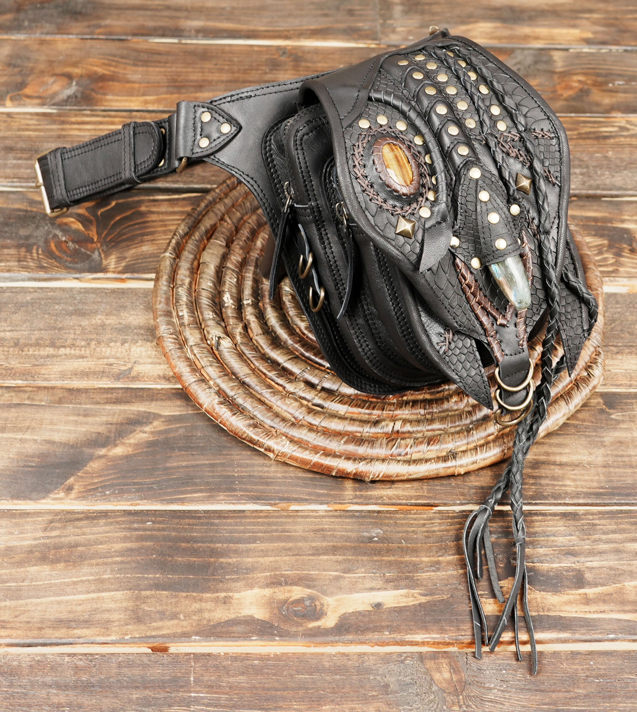 Festival-ready black leather hip bag with brass studs and braided details