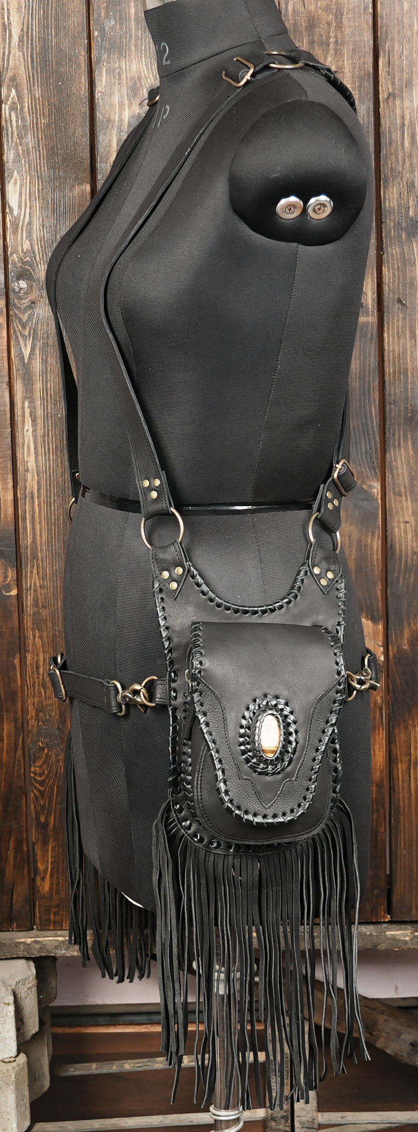 Black leather bag with fringe and studs on a wooden background