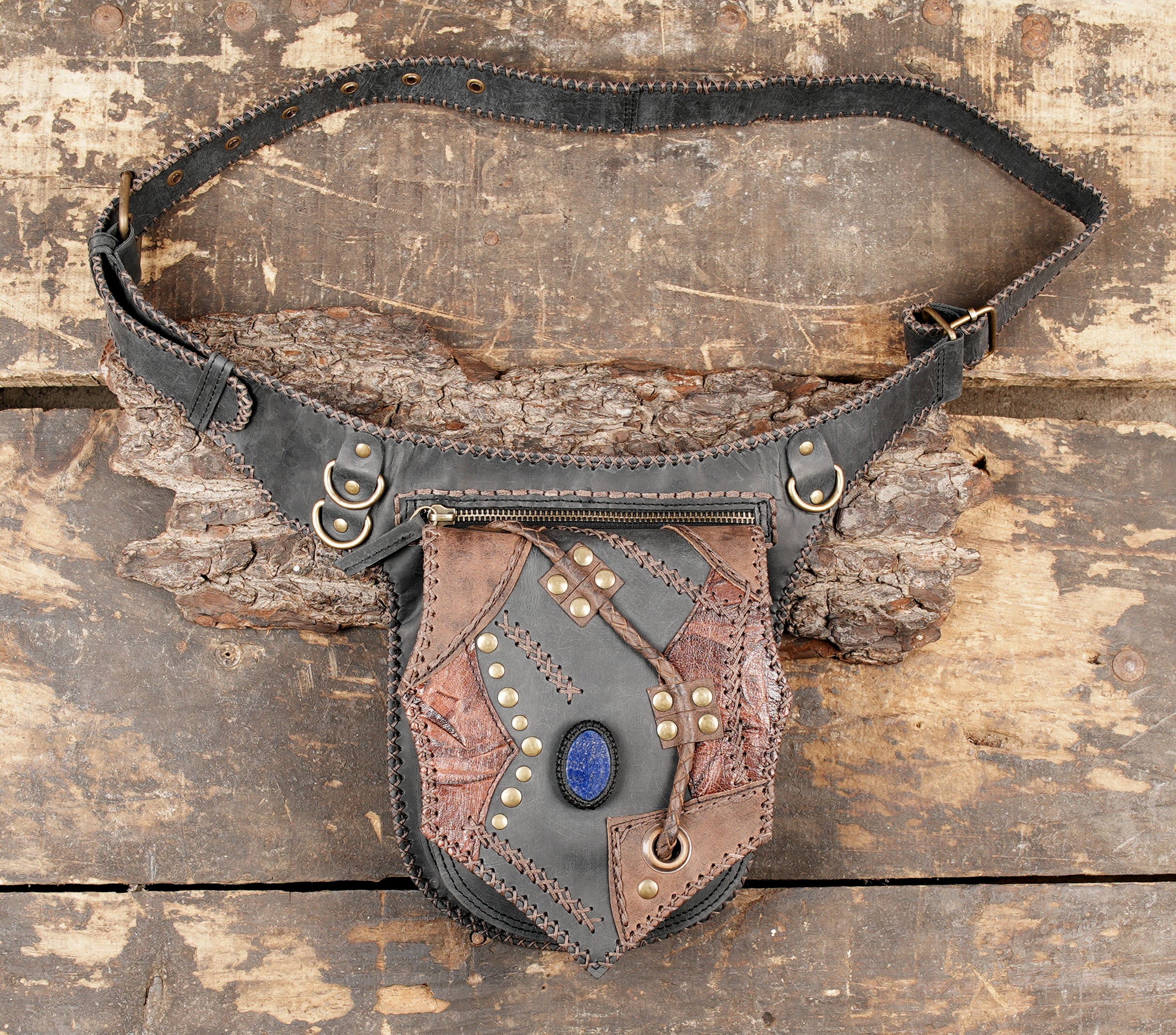 Brown leather hip pouch with black accents and gemstone centerpiece