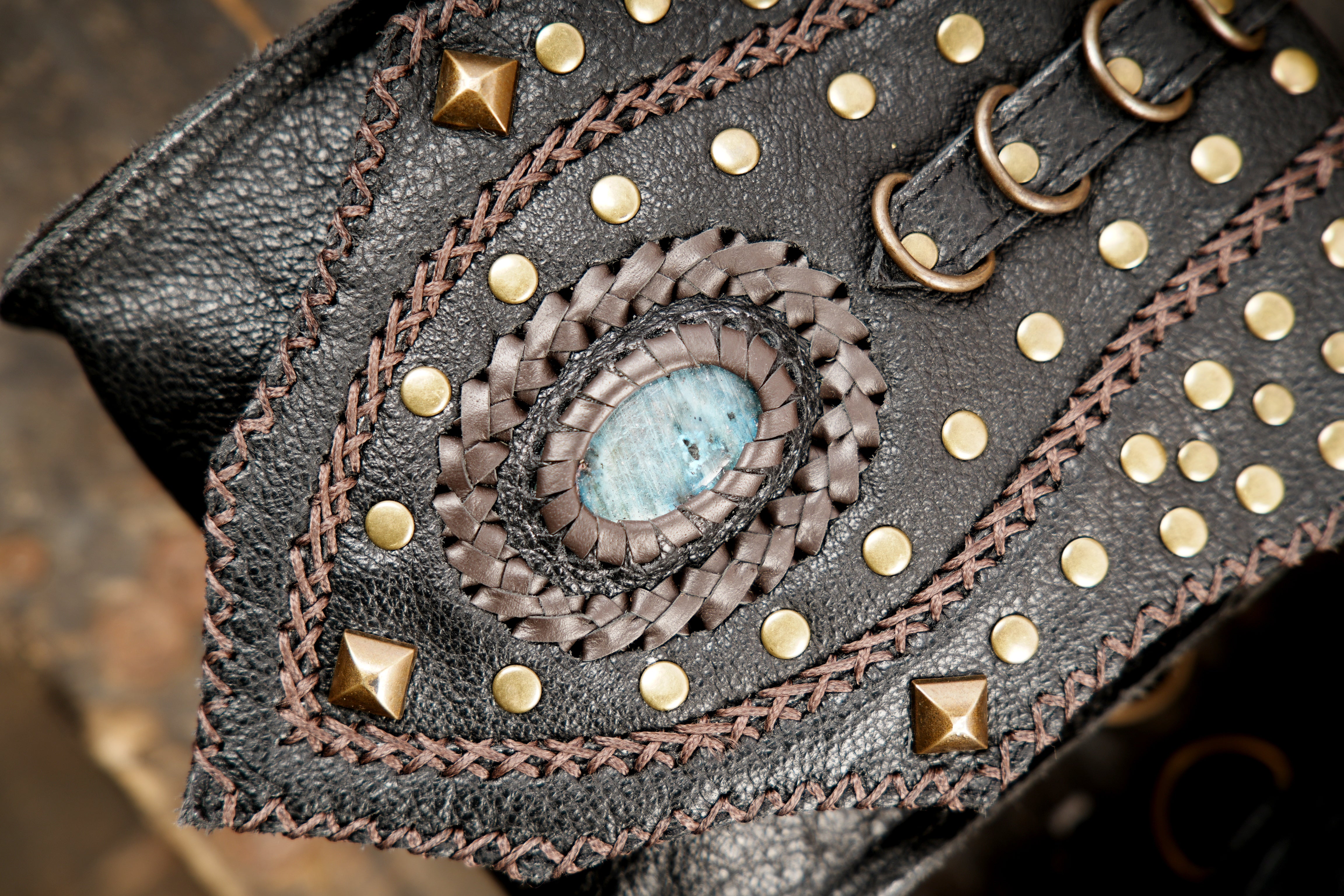 “Studded black leather holster set with braided details and gemstone centerpiece”
