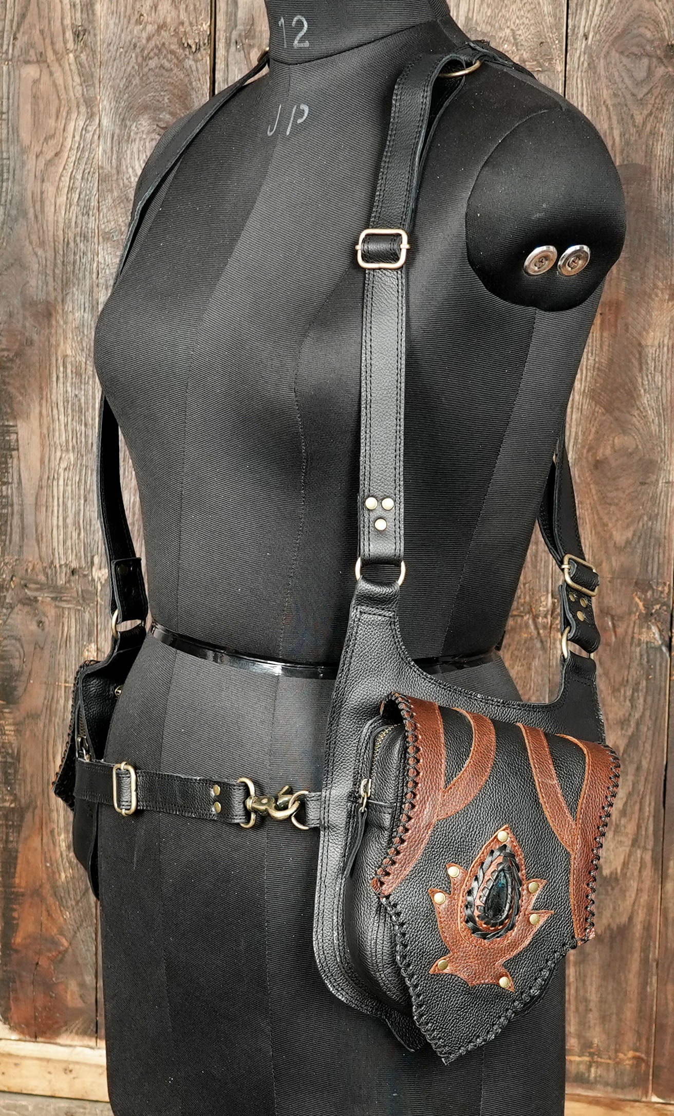 Back view of black leather holster bag showing durable straps and metal hardware.