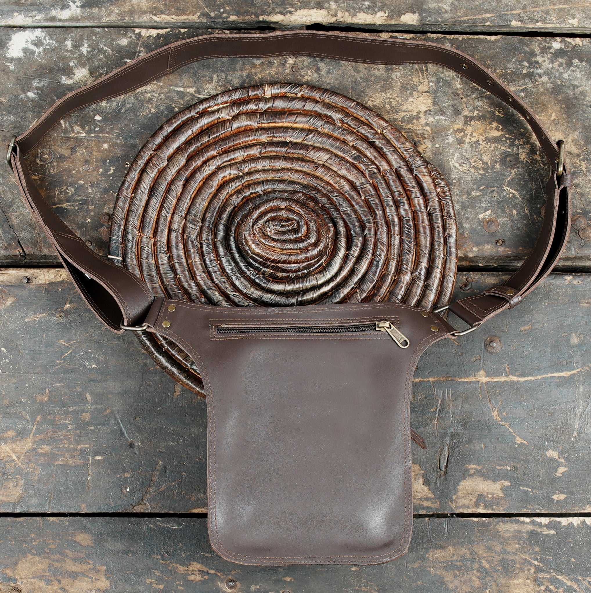 Open brown leather waist bag showing compartments with phone and wallet inside