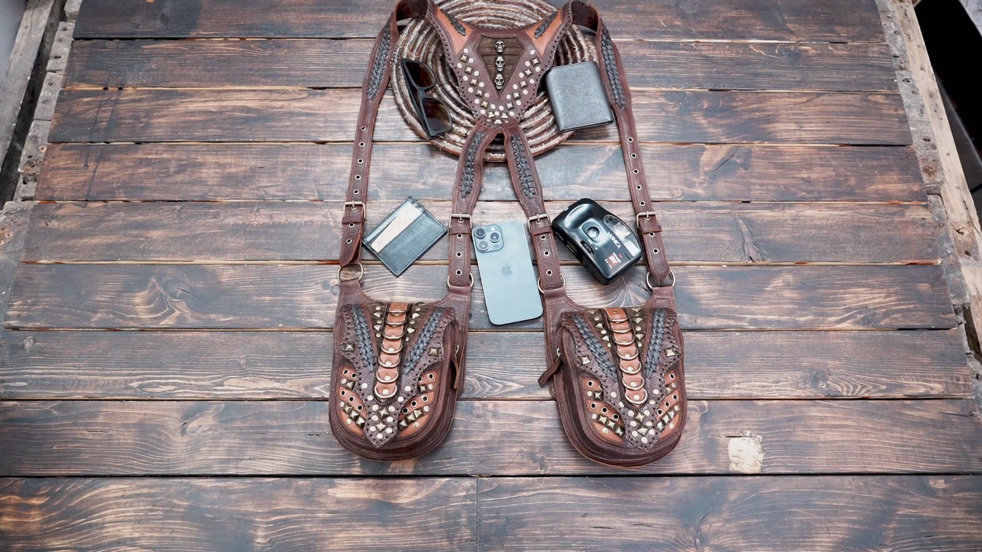 “Brown leather shoulder holster bag with carved accents and braided straps”