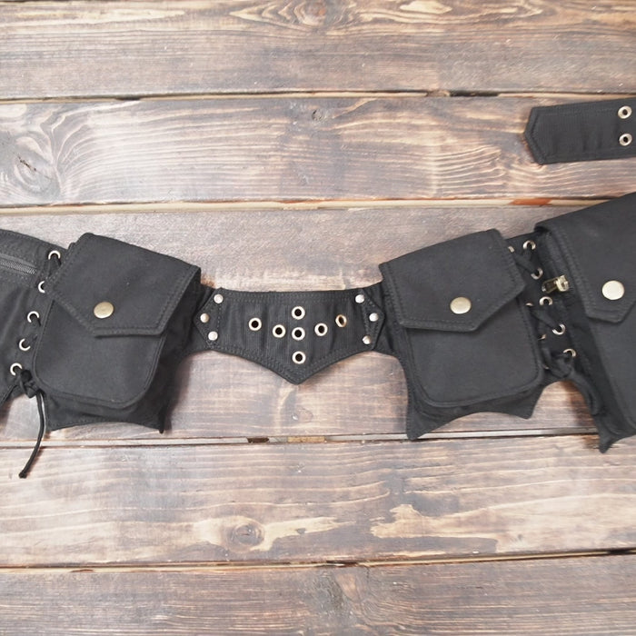 Black leather waist belt bag with multiple pockets on wooden background